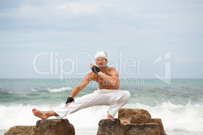 healthy man doing pilates yoga meditation on beach summer