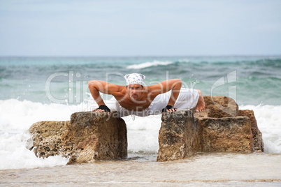 healthy man doing pilates yoga meditation on beach summer