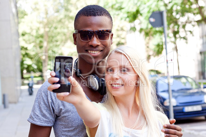 young smiling multiracial couple taking foto by smartphone