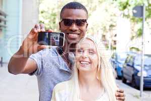 young smiling multiracial couple taking foto by smartphone