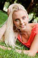 beautiful young blonde girl lying in grass summertime