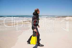 male diver with diving suit snorkel mask fins on the beach