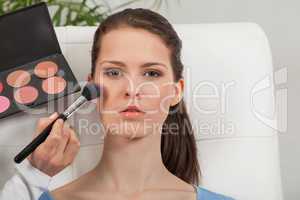 apllying powder rouge make up on face portrait