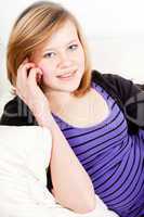 teenager girl smiling and lying on couch with mobile phone