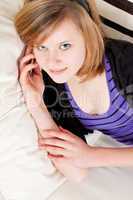 teenager girl smiling and lying on couch with mobile phone