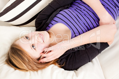 teenager girl smiling and lying on couch with mobile phone