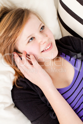 teenager girl smiling and lying on couch with mobile phone