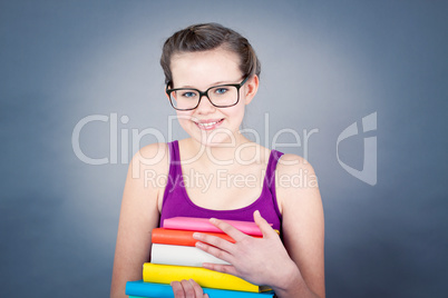 Silly smiling schoolgirl with glasses and lots of books