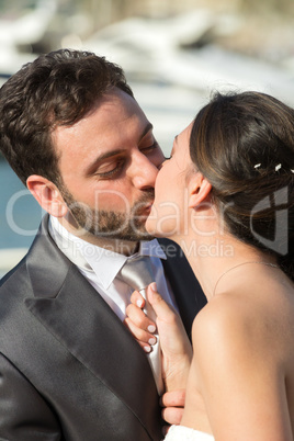 Bride pulls the tie of the groom while kissing him.