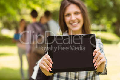 Smiling student with a shoulder bag and showing screen at tablet