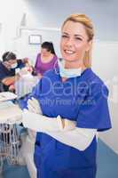 Nurse with folded arms with patient and dentist behind her