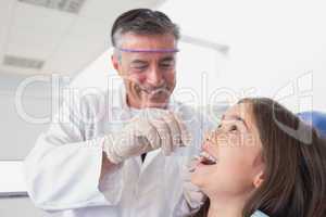 Pediatric dentist using dental floss to his young patient