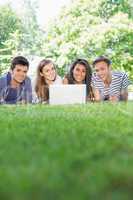 Happy students using laptop outside