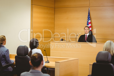 Unsmiling judge with american flag behind him