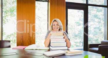 Smiling blonde mature student with stack of books