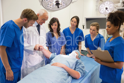 Medical students and professor checking pulse of student