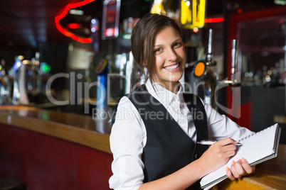 Happy barmaid writing in notepad