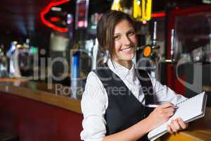 Happy barmaid writing in notepad