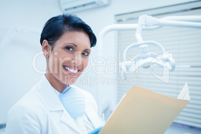 Smiling female dentist reading reports
