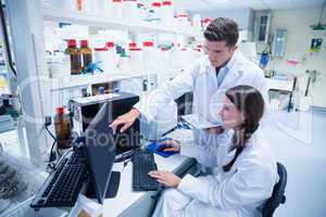 Chemist team working together at desk using computer