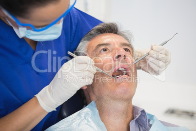 Dentist examining a patient with tools