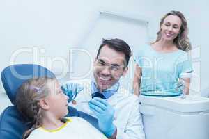 Dentist examining girls teeth with assistant