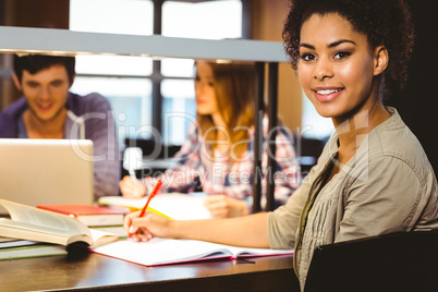 Smiling student sitting at desk writing on notepad