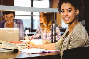 Smiling student sitting at desk writing on notepad