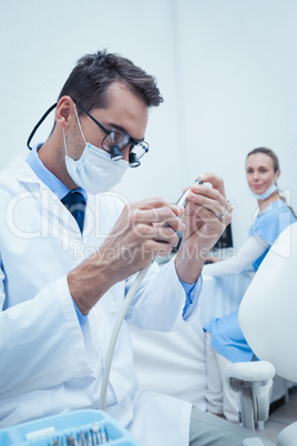 Concentrated dentist looking at dental tool