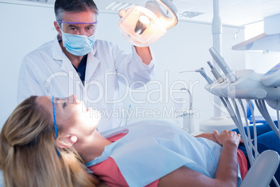 Dentist examining a patients teeth in chair under bright light