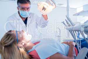 Dentist examining a patients teeth in chair under bright light