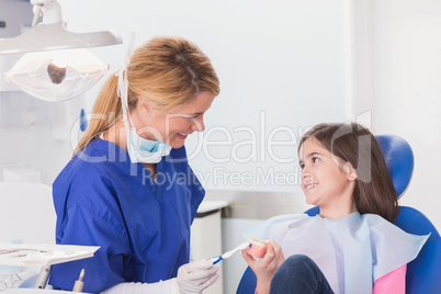 Smiling dentist teaching to her young patient how use toothbrush