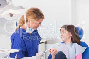 Smiling dentist teaching to her young patient how use toothbrush