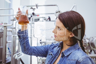 Stylish brunette in denim jacket looking at beaker of beer