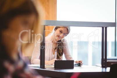 Smiling student sitting next to the window taking notes