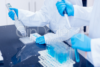 Science students using pipettes to fill test tubes