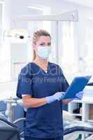 Dentist in mask using her tablet and looking at camera