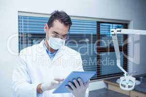 Dentist in surgical mask using digital tablet
