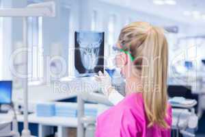 Female dentist in pink scrubs examining x-ray