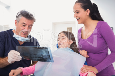 Pediatric dentist explaining to young patient and her mother the