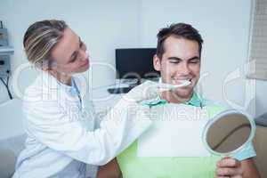 Female dentist brushing mans teeth