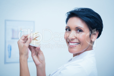 Smiling female dentist holding mouth model