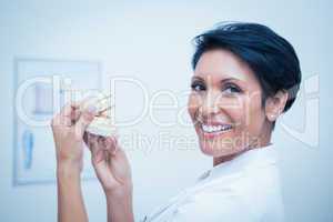 Smiling female dentist holding mouth model