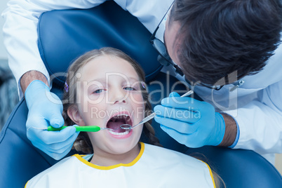 Male dentist examining girls teeth