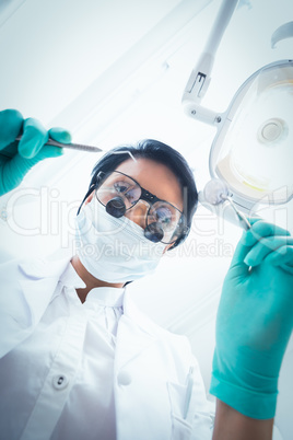 Female dentist in surgical mask holding dental tools