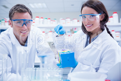 Smiling chemists working together looking at camera