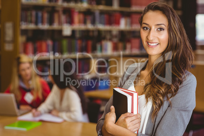 Pretty student holding books with classmates behind her