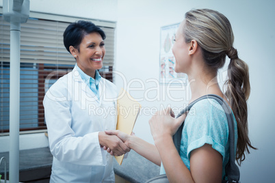 Female dentist shaking hands with woman