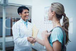 Female dentist shaking hands with woman