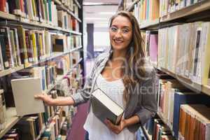 Pretty student picking out a book in library